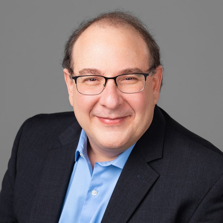 A person in a suit and glasses Description automatically generated
